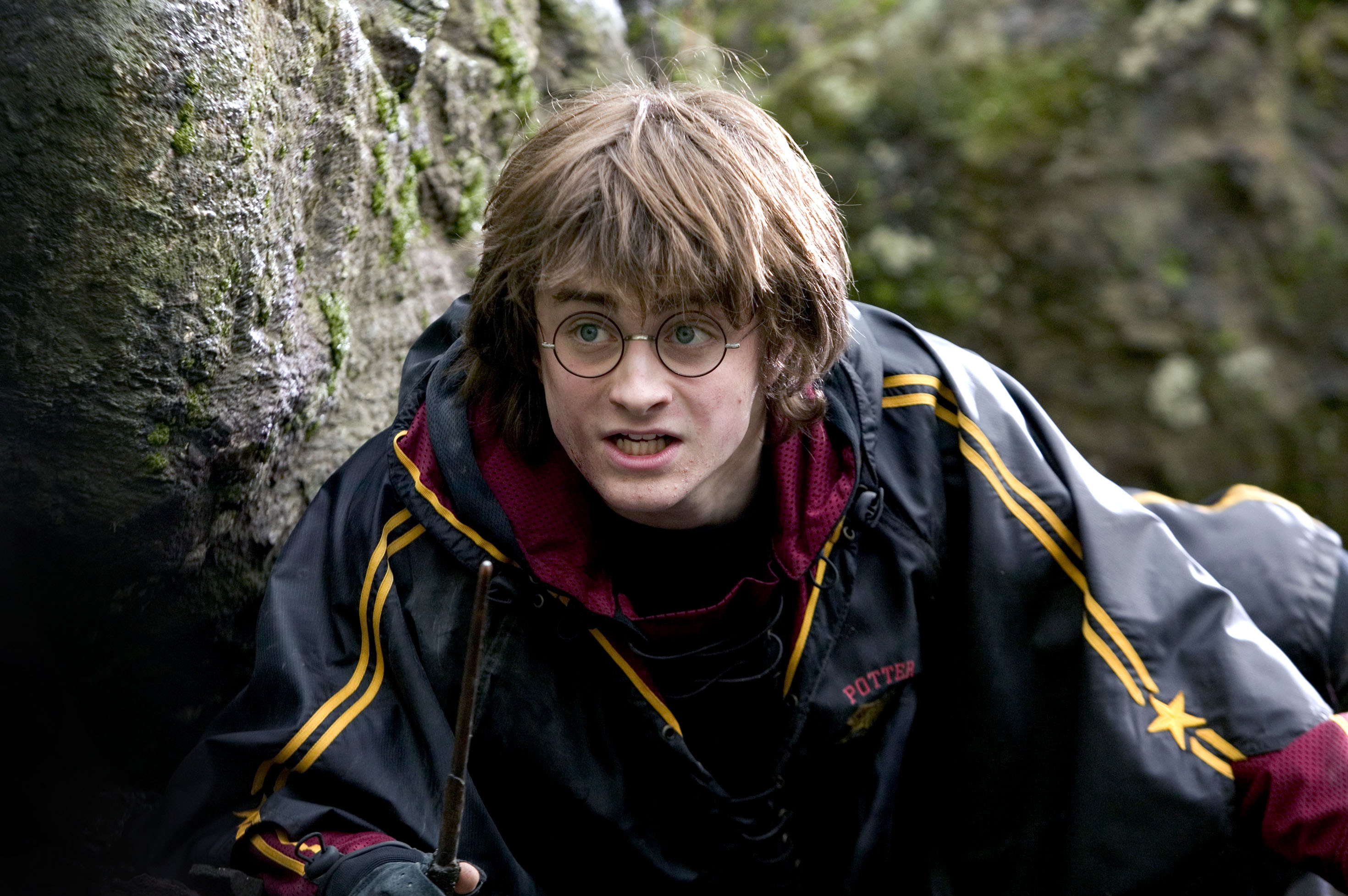 Harry Potter in a Quidditch robe, with a wand, looking surprised