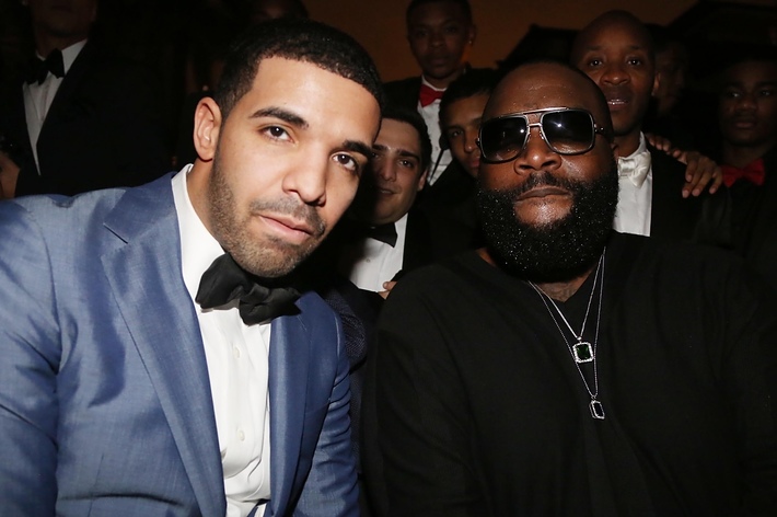 Drake in a blue suit with black bow tie next to Rick Ross in a black jacket at a music event