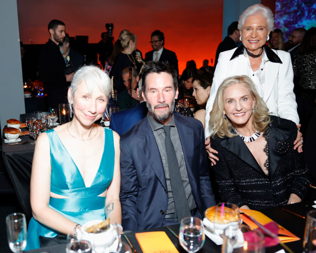 Alexandra Grant, Keanu Reeves, and others posing at a table at an event