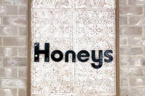 彫刻のディテールが施された背景に「Honeys」と書かれたサインが掲げられた壁