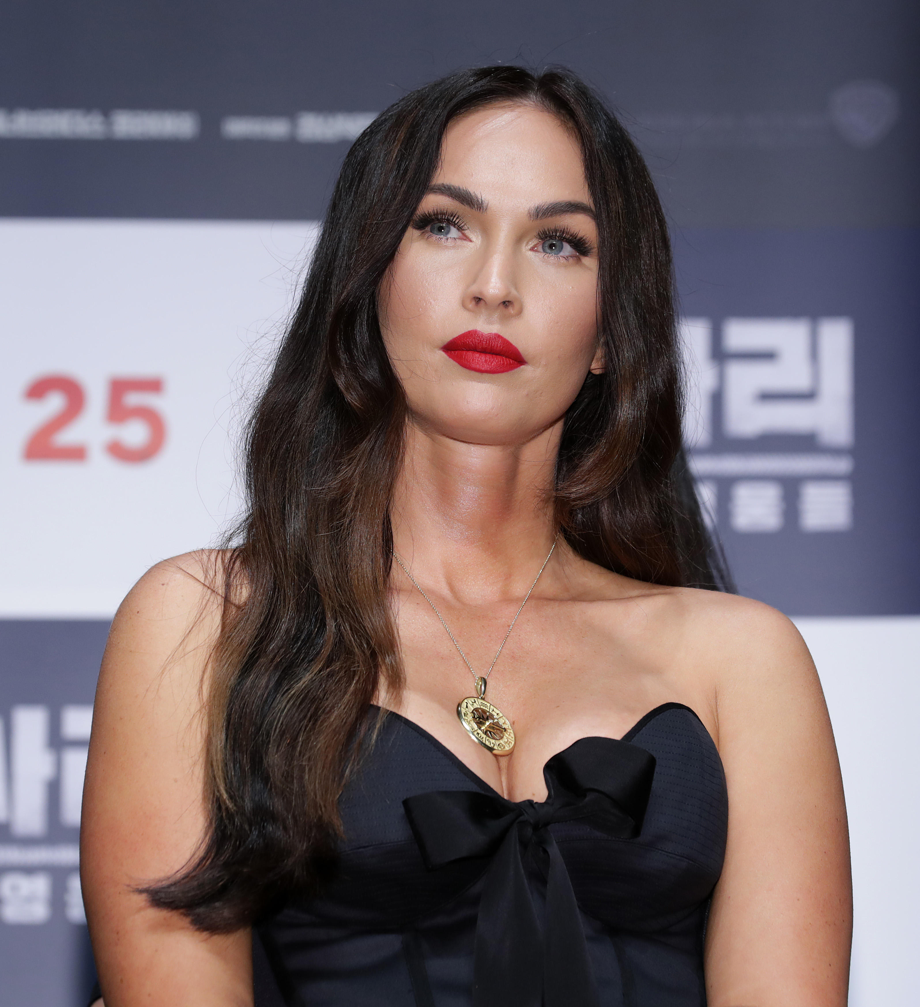 Megan Fox poses at an event in a dress with a bow detail