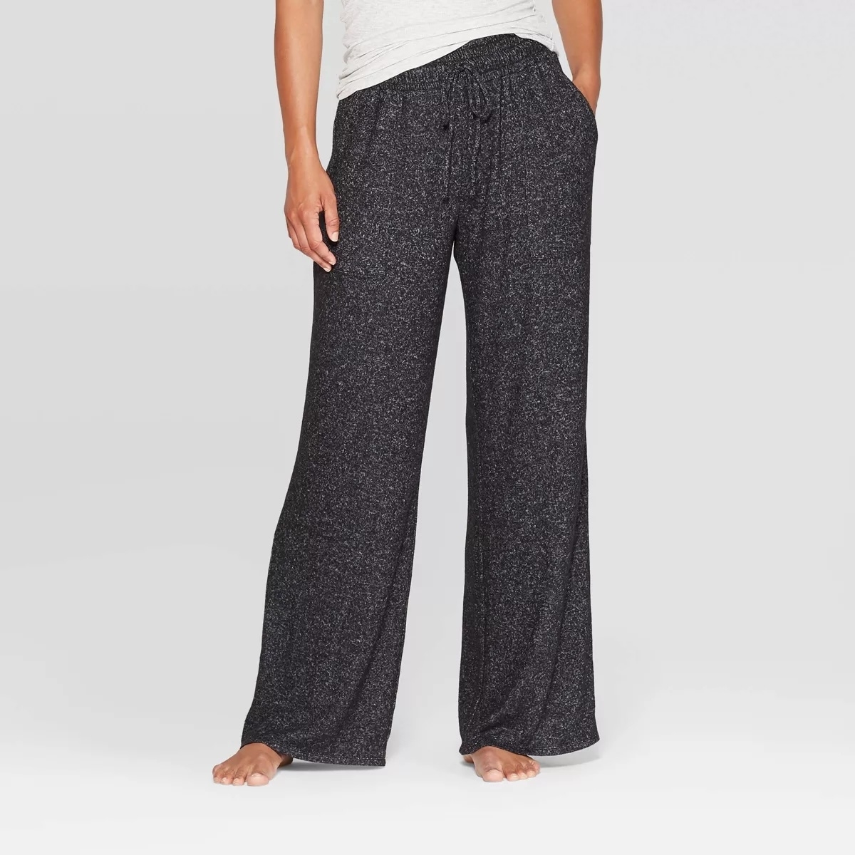 Person modeling loose-fitting, casual black speckled pants suitable for leisure or shopping