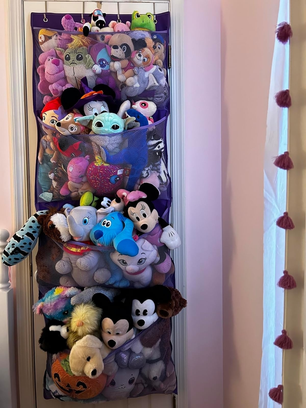 A hanging organizer filled with various plush toys including Disney characters.