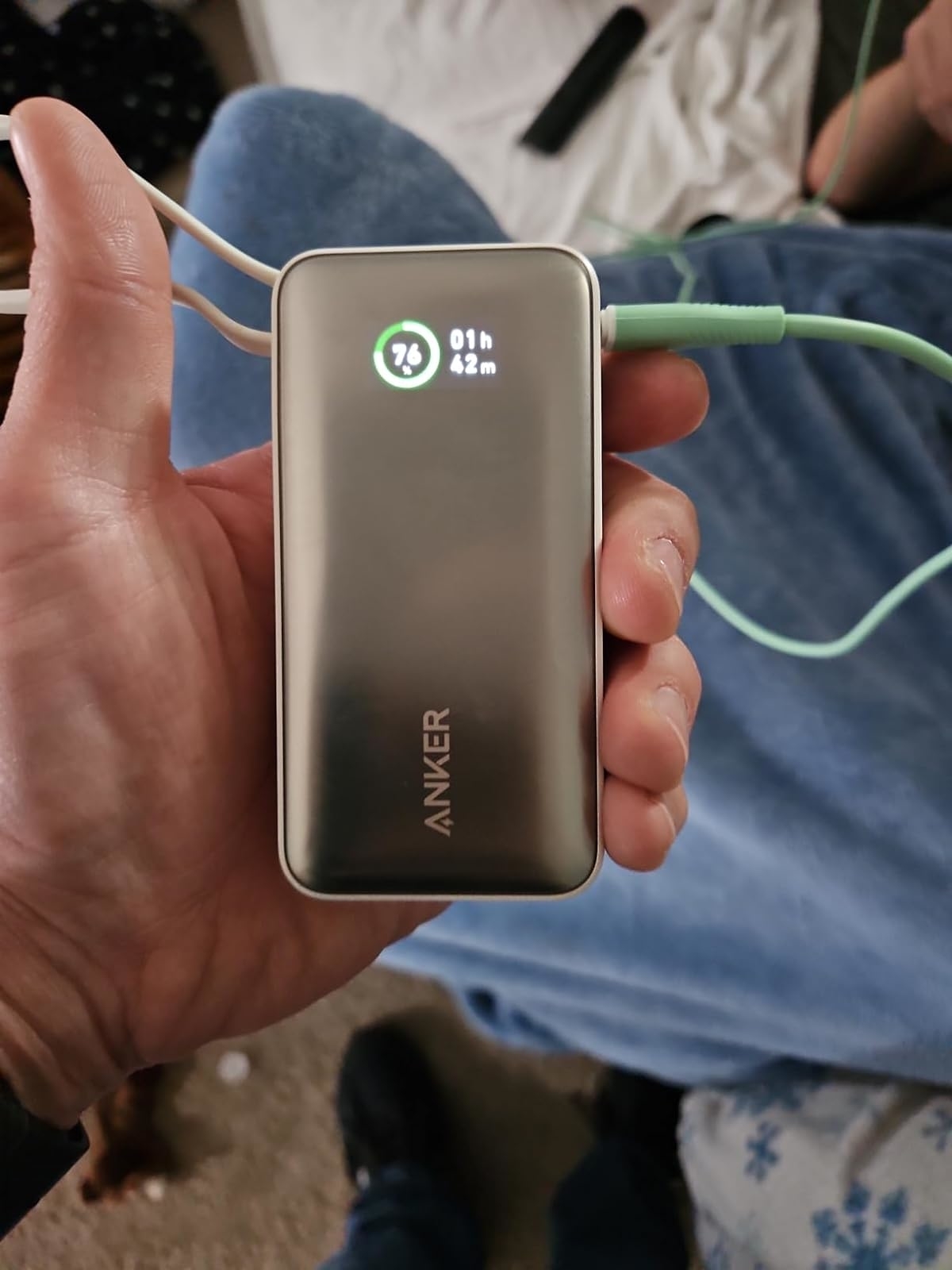 Reviewer holding an Anker portable charger displaying 73% charged, cords attached.