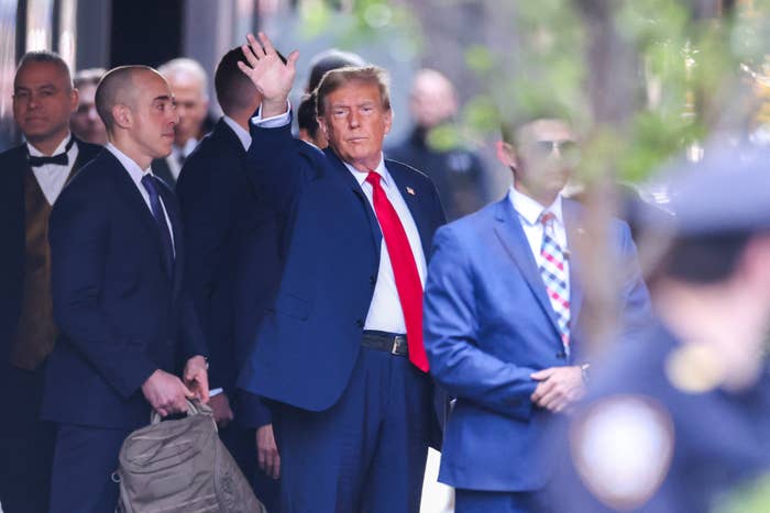 Donald Trump waving as he exits a building