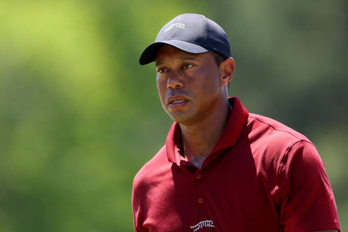 Tiger Woods in a red shirt and cap looks focused during a golf tournament