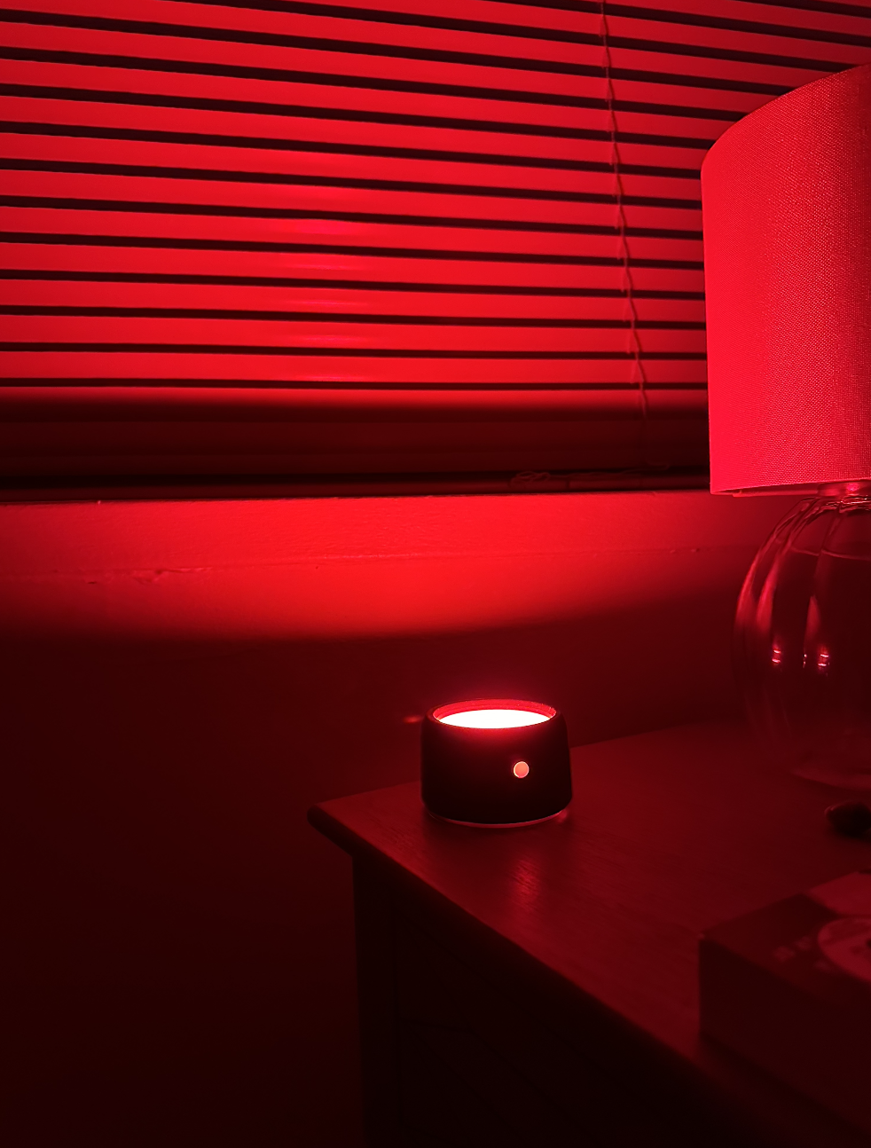 Smart speaker on a nightstand illuminated by red light