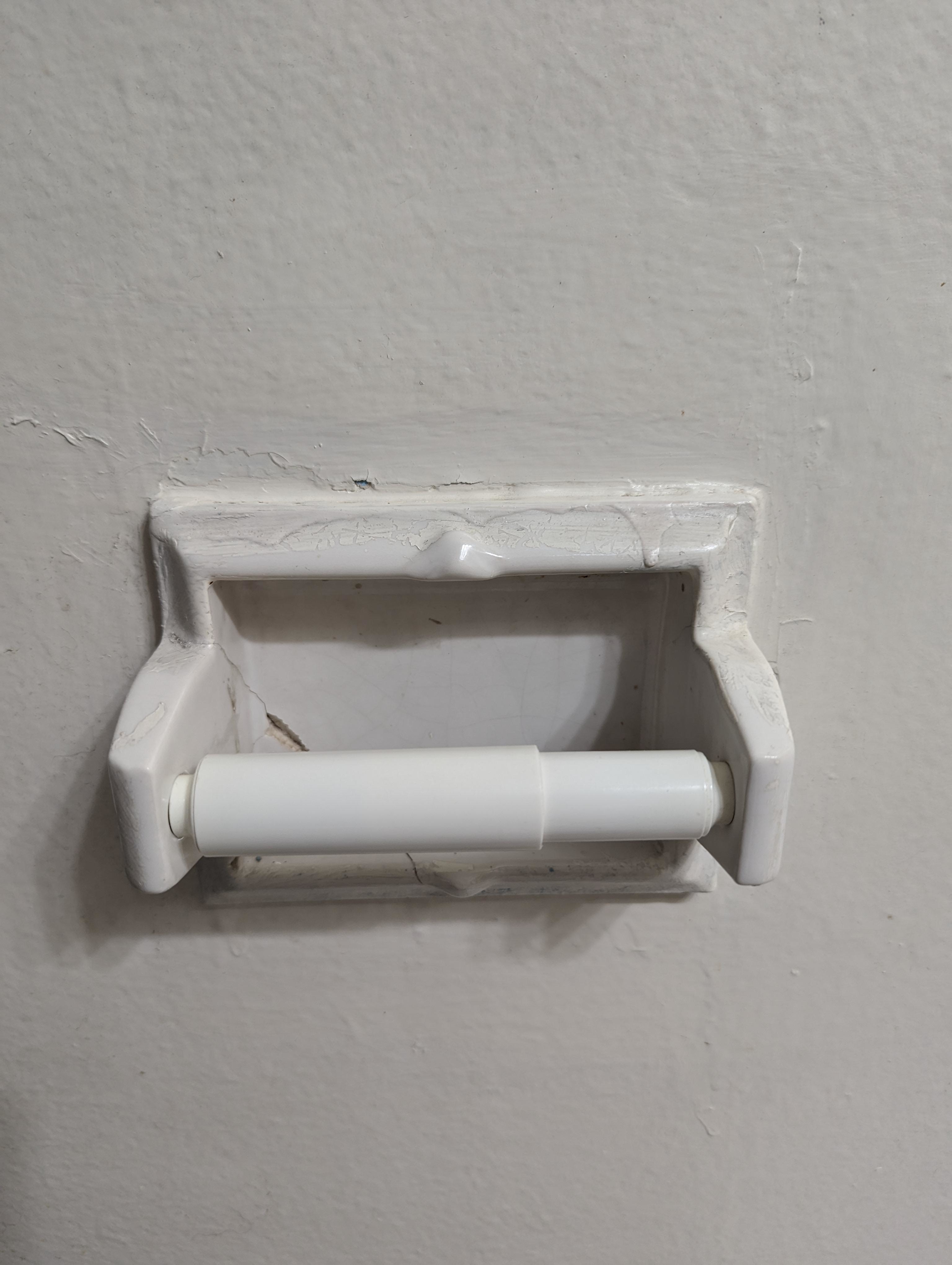 An empty toilet paper holder mounted on a wall