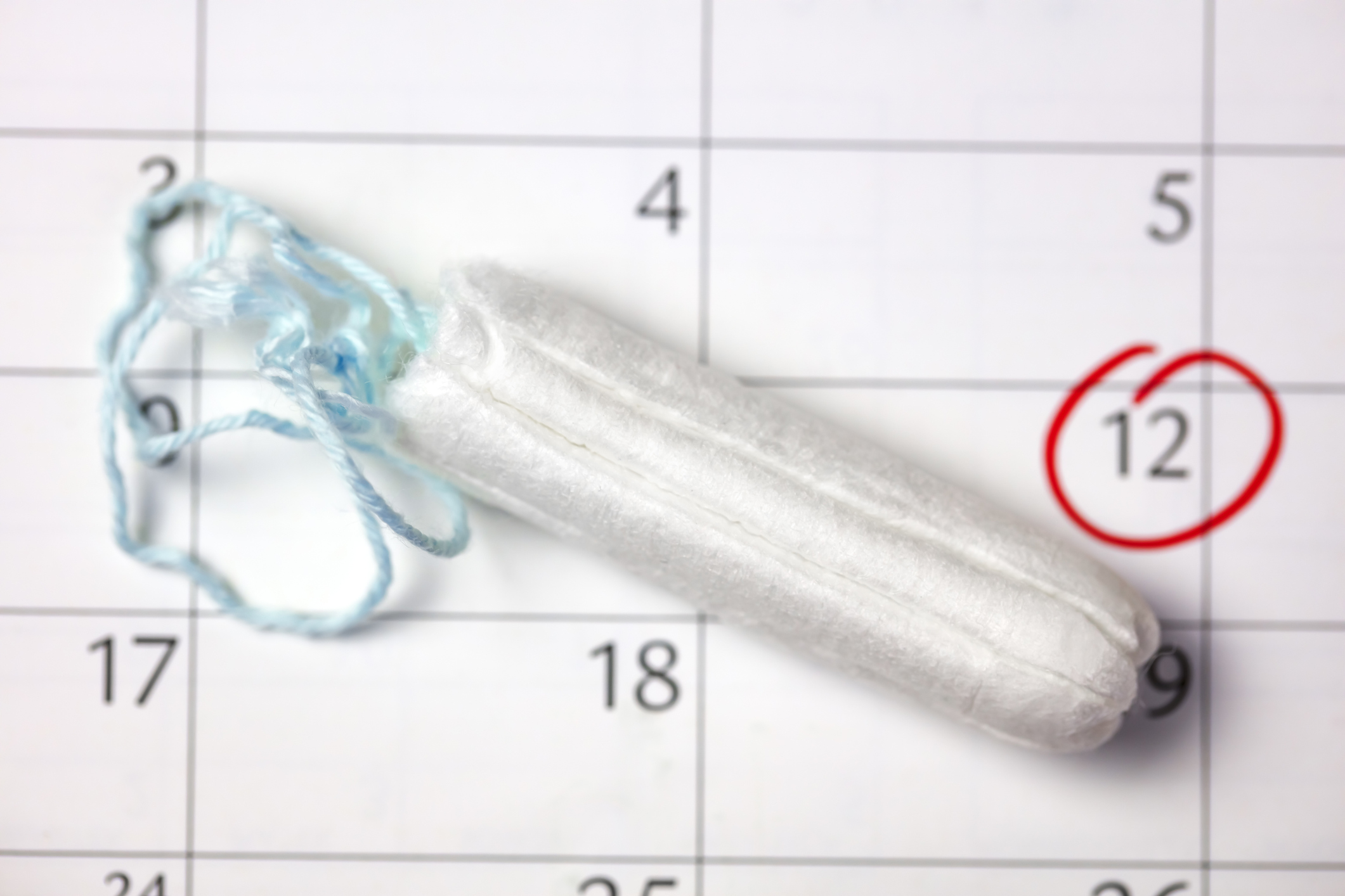 Tampon on a calendar highlighting date 12, implying menstrual cycle tracking for work absence planning