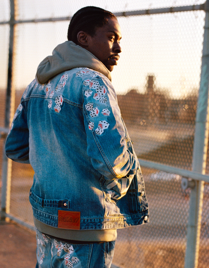 Man in a denim jacket with card pattern detailing, looking away from the camera