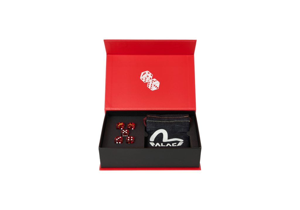 Open red box with a pair of dice inside and a folded black fabric with a swan-like logo