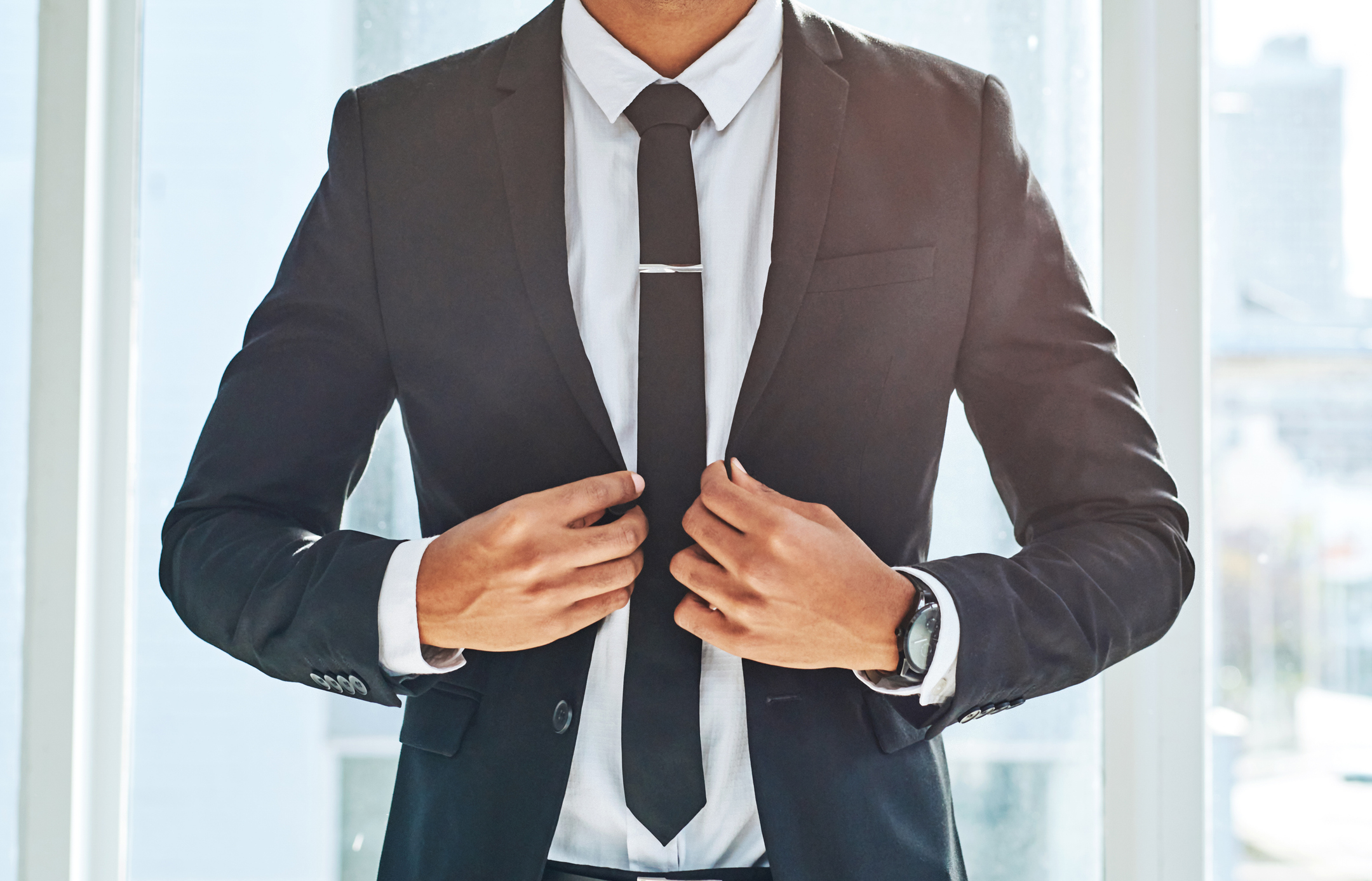 Professional in a suit adjusting tie, representing business attire for Work &amp;amp; Money article