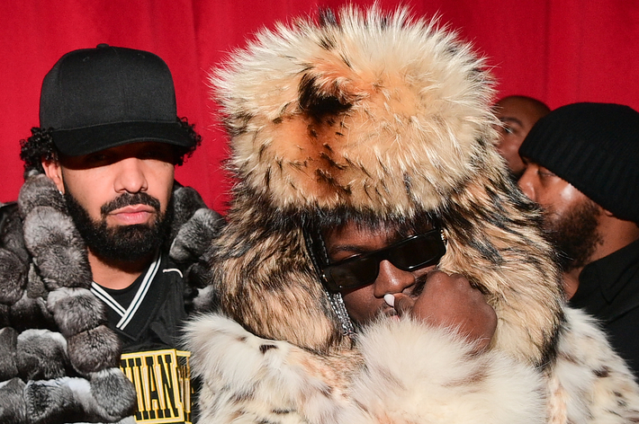 Drake in a black hat and jacket next to Lil Yachty in a large fur coat and hat, both at an event