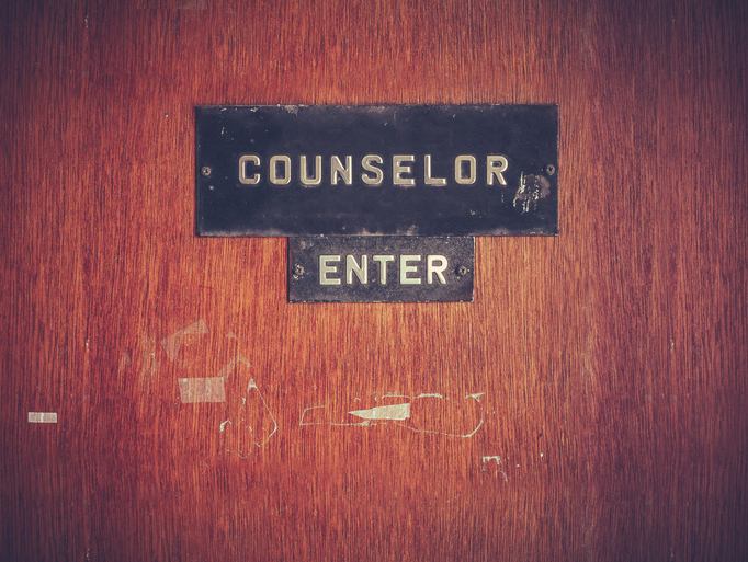A worn wooden door with a sign reading &quot;COUNSELOR&quot; above a smaller &quot;ENTER&quot; sign