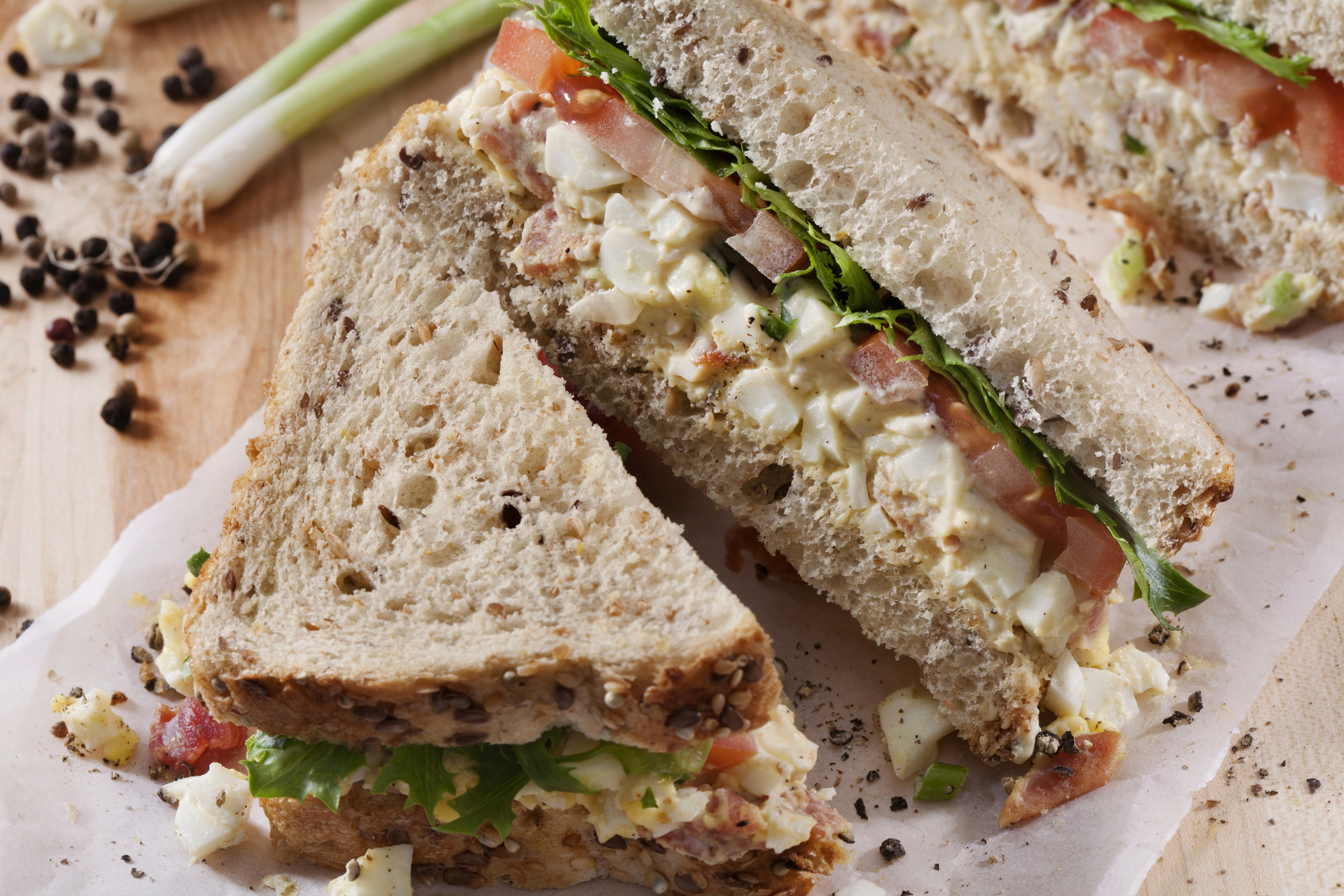Egg salad sandwich with lettuce and tomato on a cutting board
