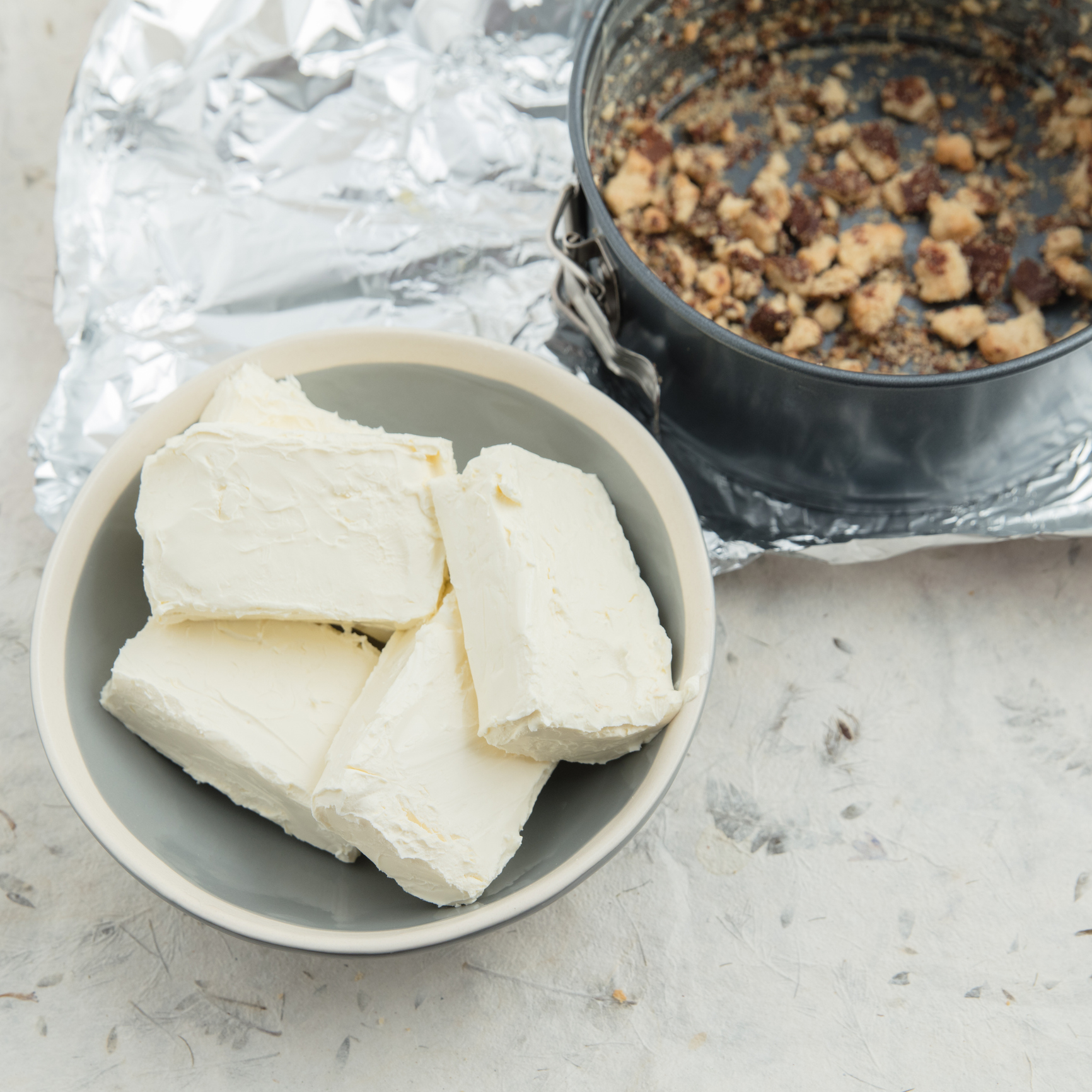 A bowl of feta cheese beside a pan of cooked food