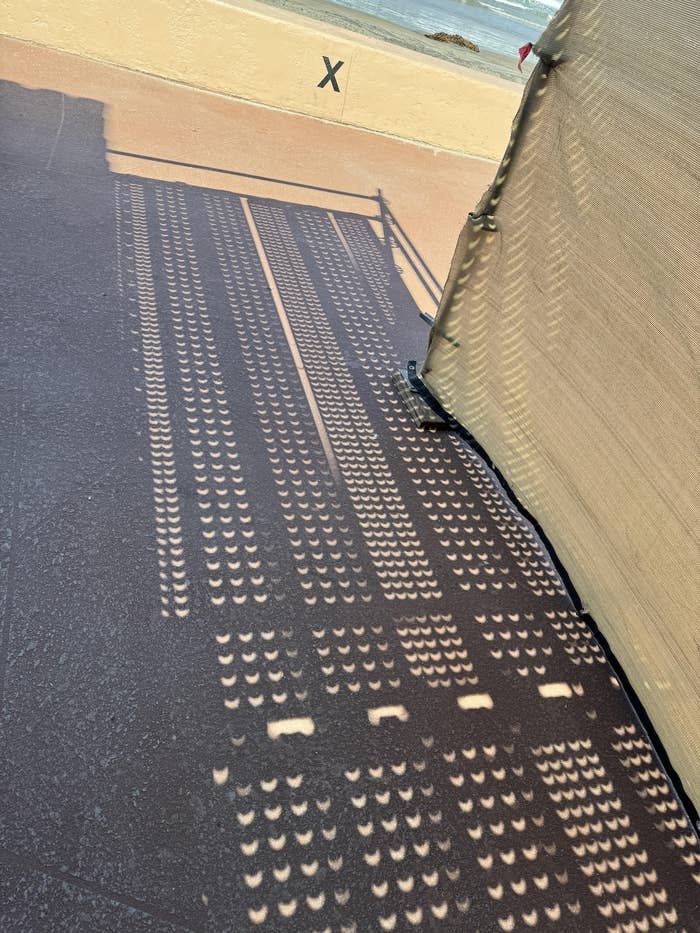 Shadow pattern on ground next to a beaded curtain casting a matrix of light spots