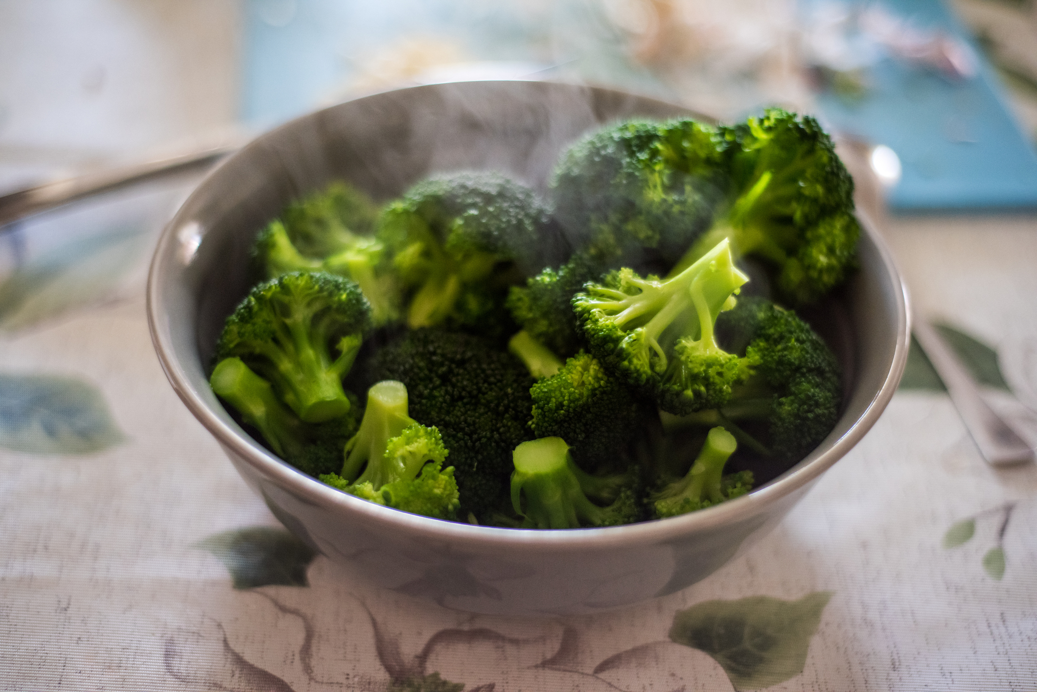 A bowl of hot, steamed broccoli on a table