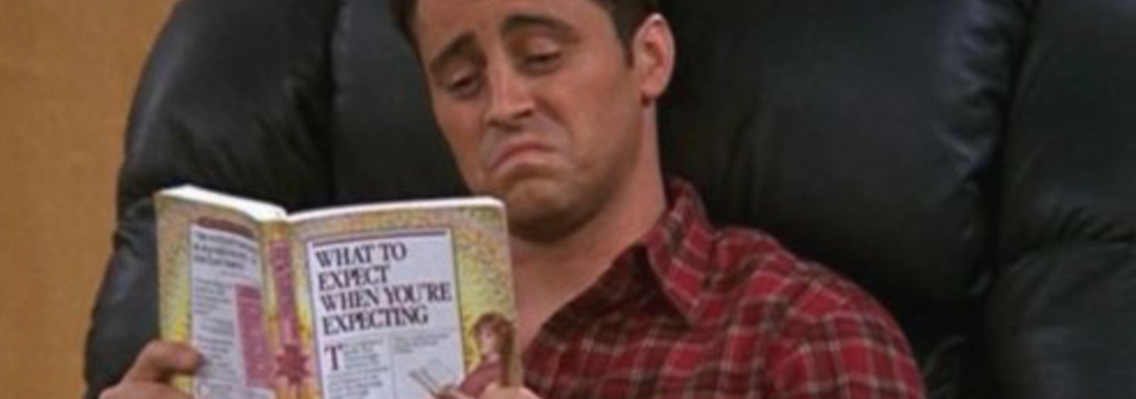 Joey from Friends looks confused reading "What to Expect When You're Expecting."