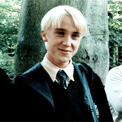 Personaje Draco Malfoy de Harry Potter sonriendo, con uniforme escolar de Hogwarts
