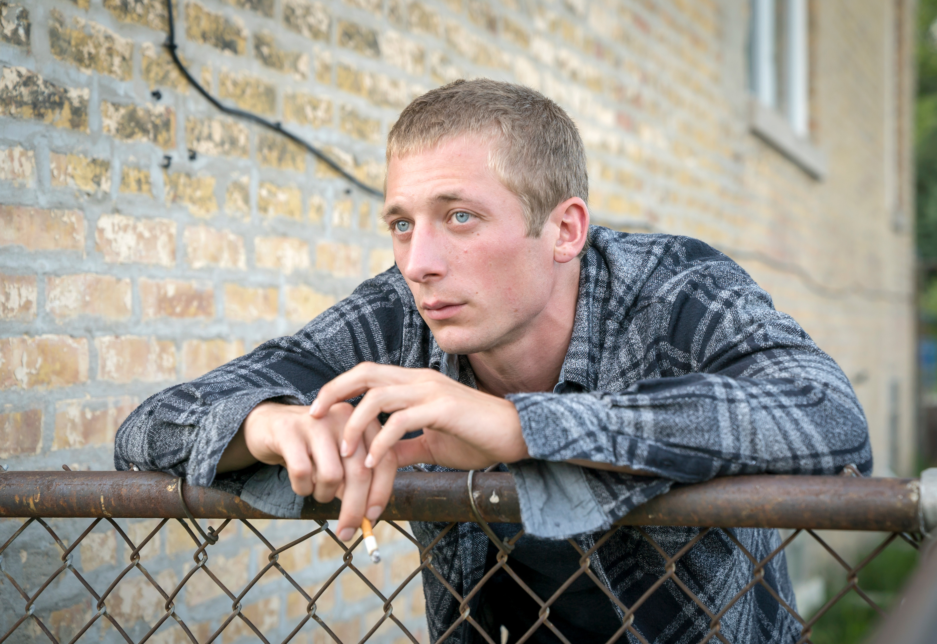 Man resting arms on a fence looking thoughtful. He&#x27;s wearing a patterned shirt. Used for a TV show article