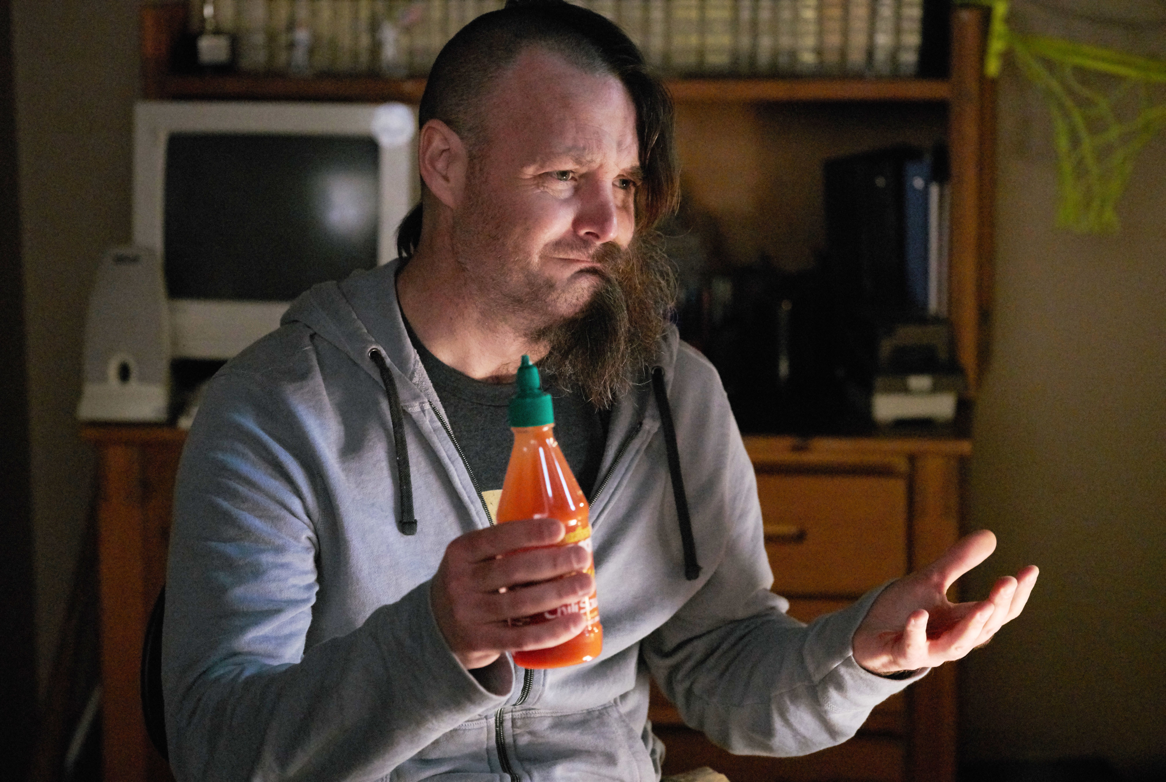 Actor in character holding a bottle, with a pensive expression, indoors