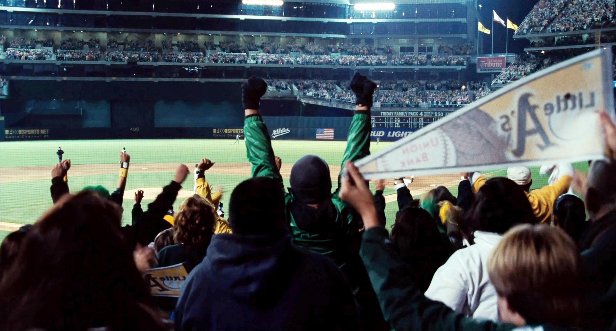 Crowd at a baseball game cheering, a person holds a sign, excitement visible