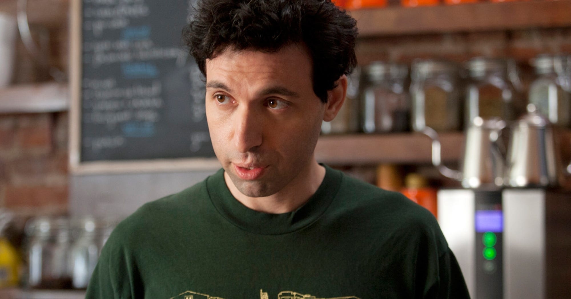 Character in a kitchen setting wearing a green t-shirt, portrayed with a puzzled expression