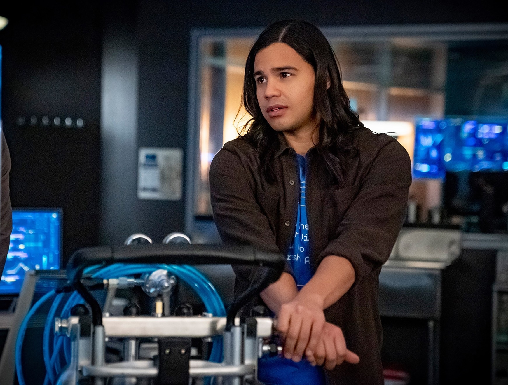 Character Cisco Ramon from TV series in a lab with tech equipment, looking pensive