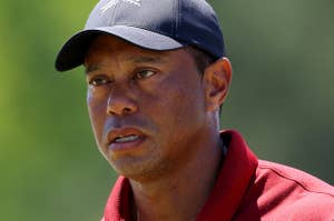 Tiger Woods in a red shirt and cap looks focused during a golf tournament