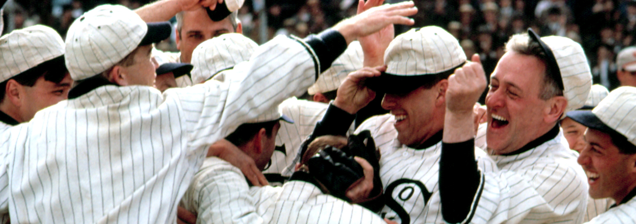 A joyful group of baseball players in white uniforms celebrating on the field.