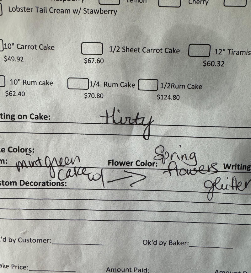 Handwritten cake order form with notes on flavor, decorations, and approval by the baker