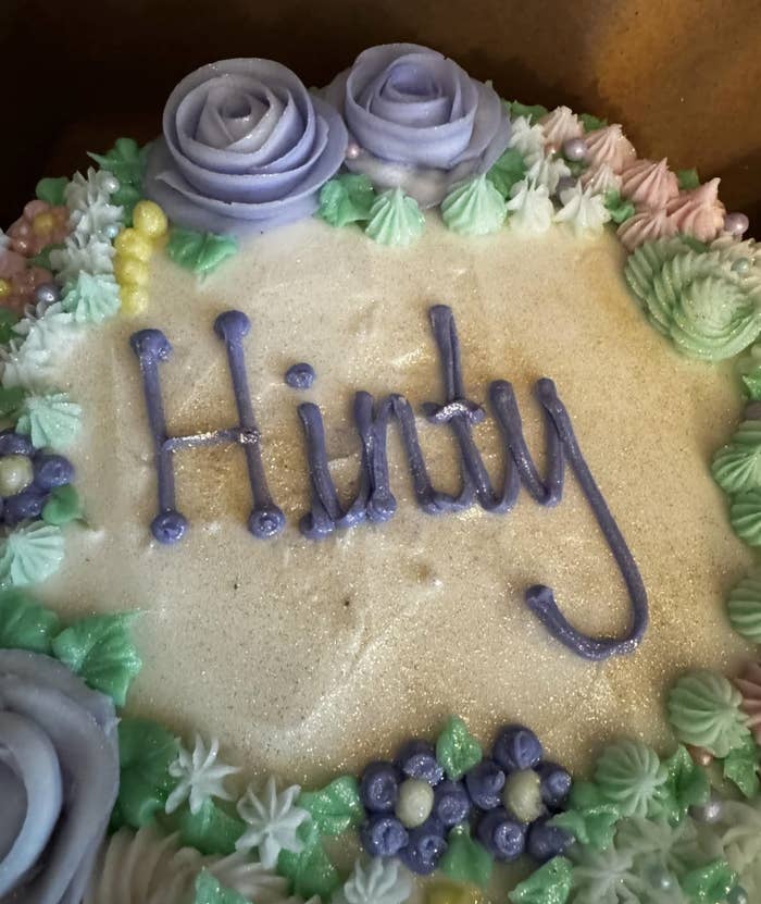 Decorative cake with &quot;Hindy&quot; written in icing, adorned with icing flowers and details