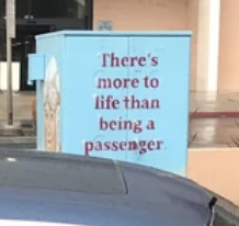 Utility box with the phrase &quot;There&#x27;s more to life than being a passenger&quot; written on it