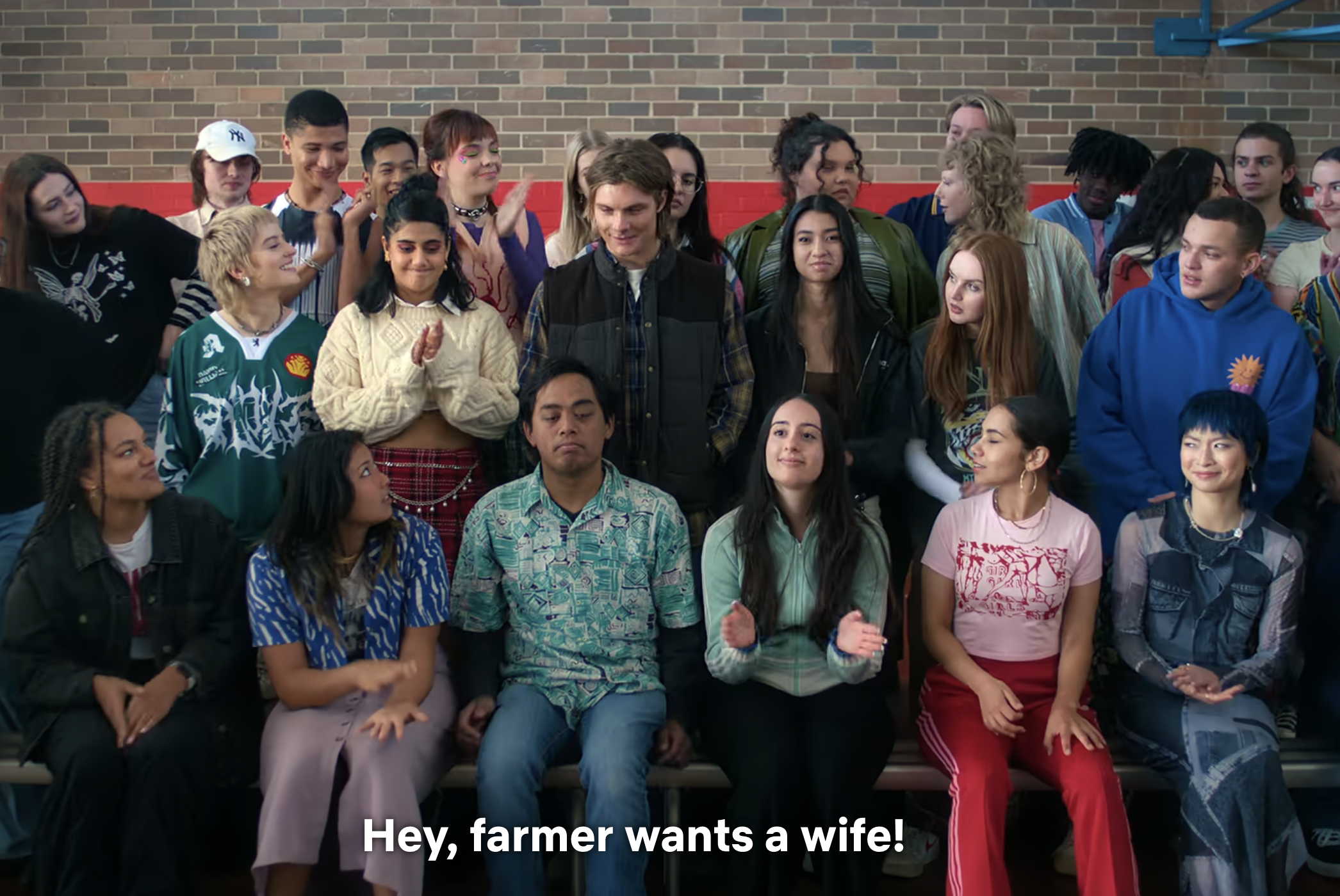Group of diverse people surrounding a central figure, expressions suggesting excitement or cheer. Text on image: &quot;Hey, farmer wants a wife!&quot;