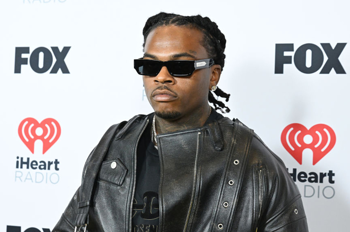 Gunna in leather jacket and sunglasses poses at iHeartRadio event