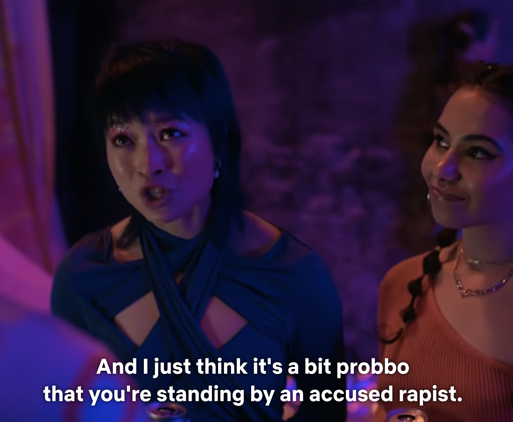 Two women talking, one wears a blue top, the other a brown dress. Subtitle: Expressing concern about supporting an accused person