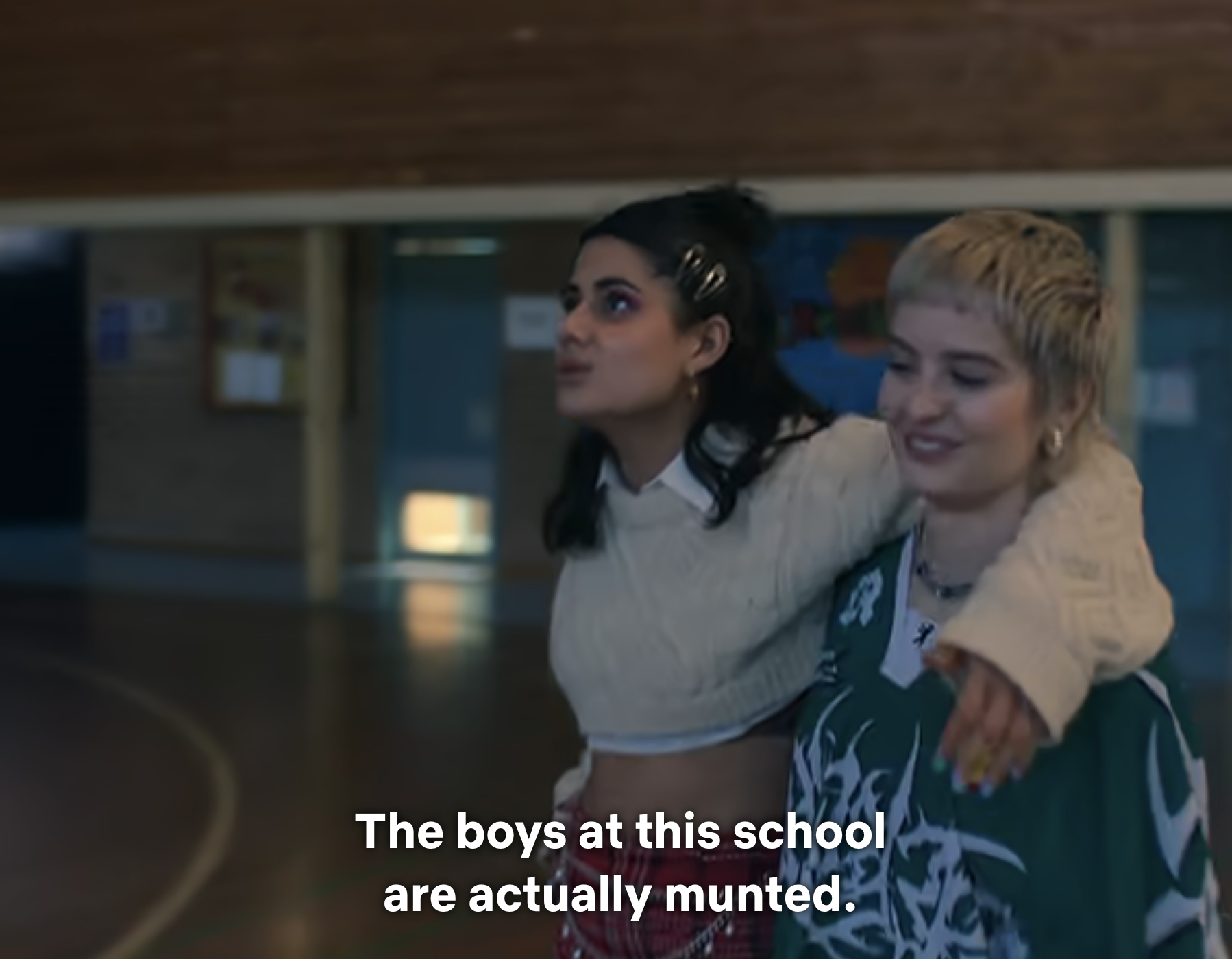 Two characters in a school hallway, one consoling the other, with a subtitle