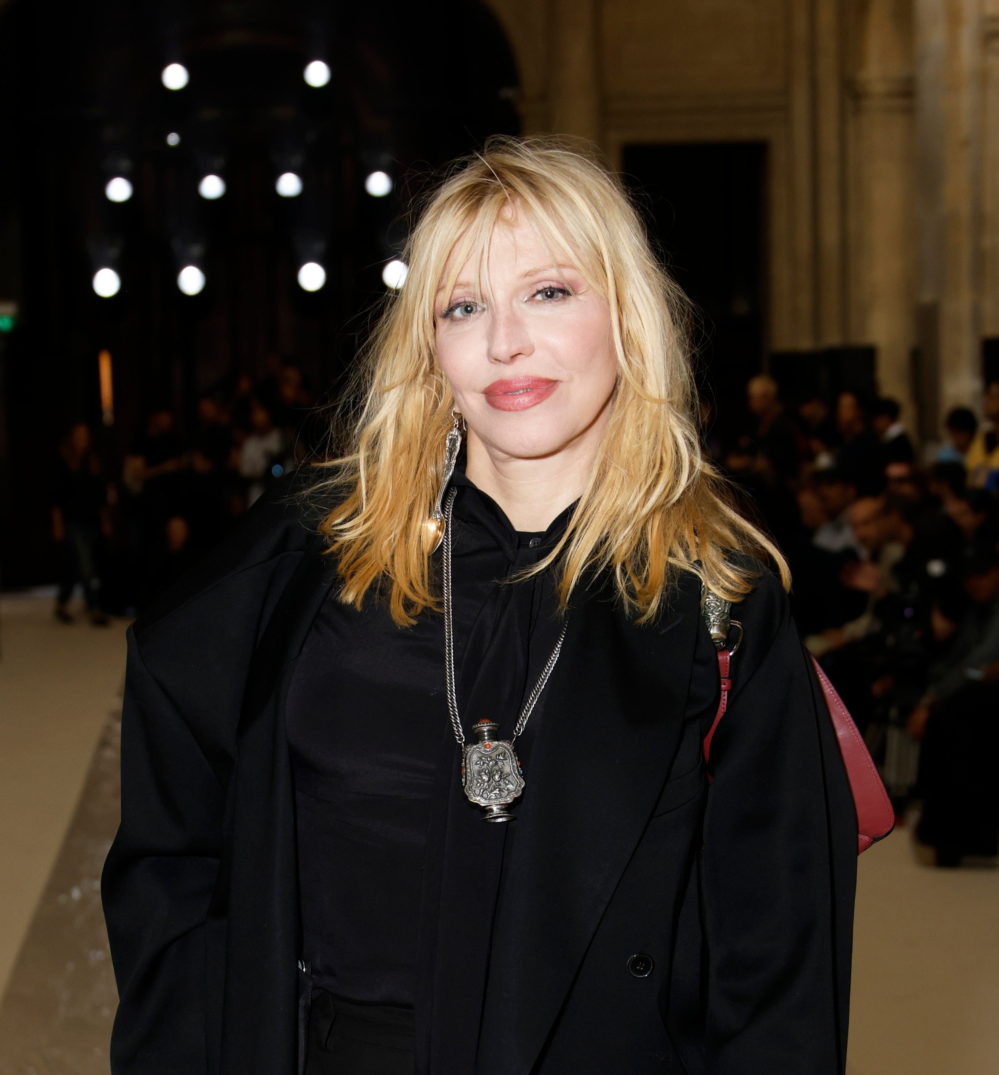 Courtney Love at an event wearing a blazer with a silver pendant