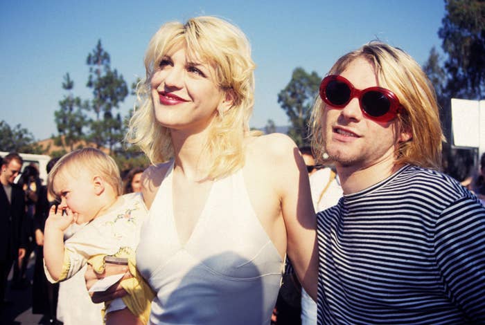 Courtney Love holding a baby and standing next to Kurt Cobain at an event