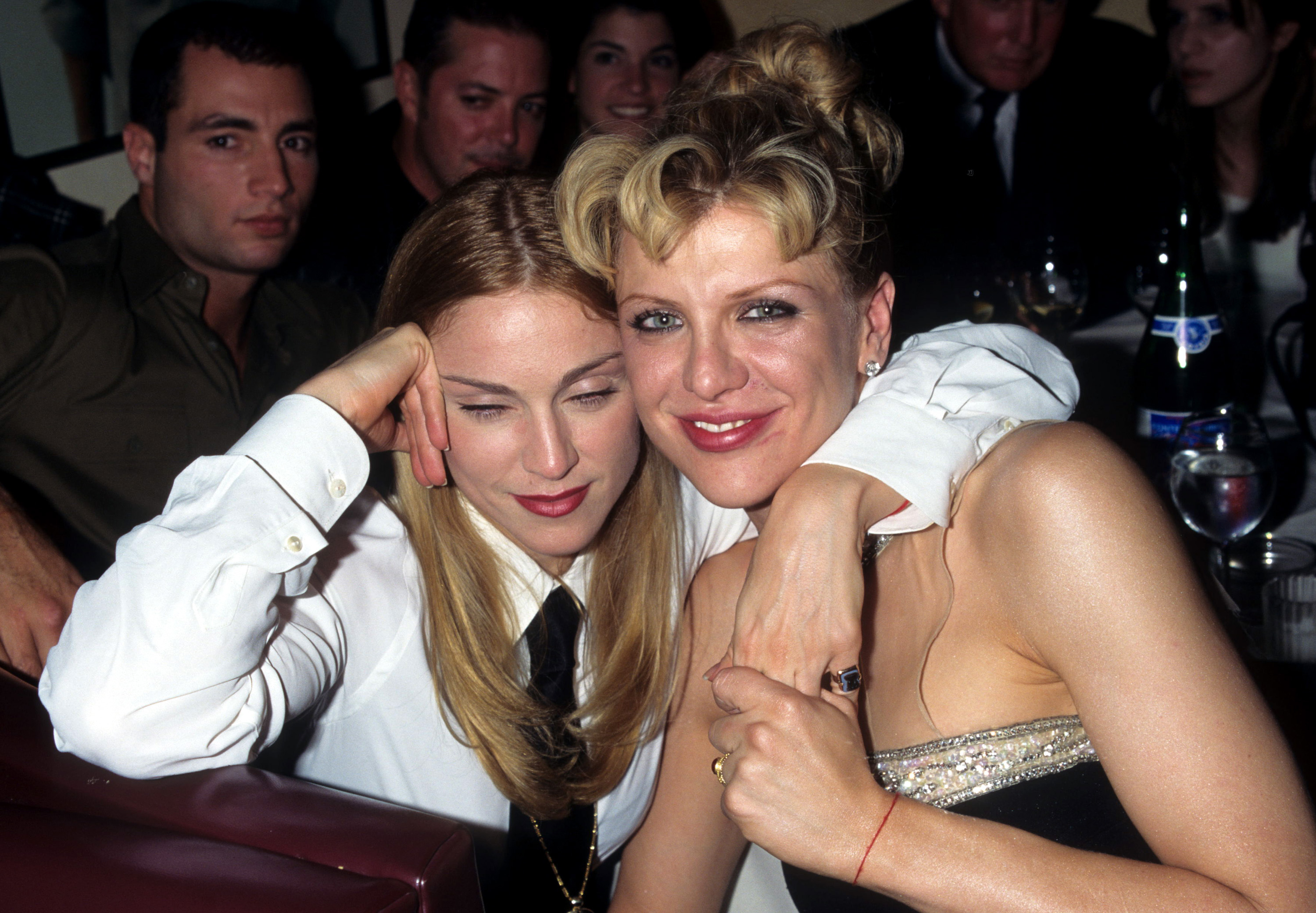 Madonna and Courtney Love with their arms around each other as they take a picture at an event