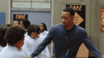 Will Smith in a sweater and slacks coaches a youth team indoors