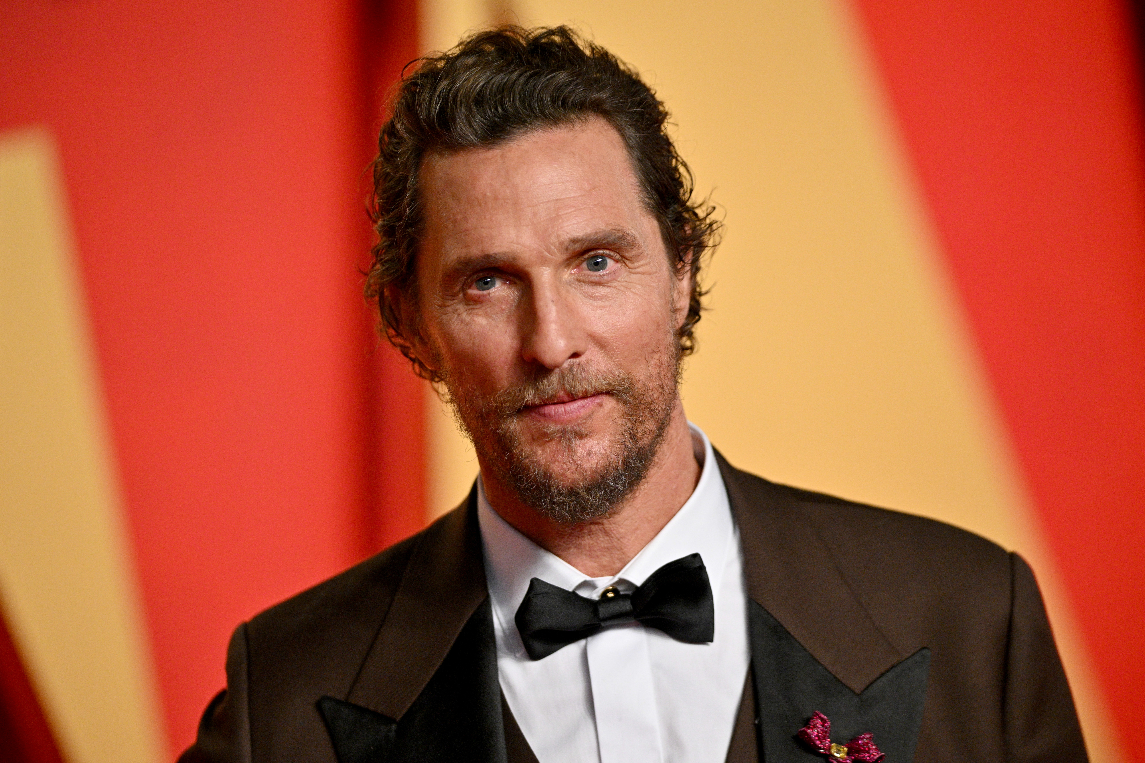 Matthew McConaughey wearing a suit with a bow tie, looking away from camera