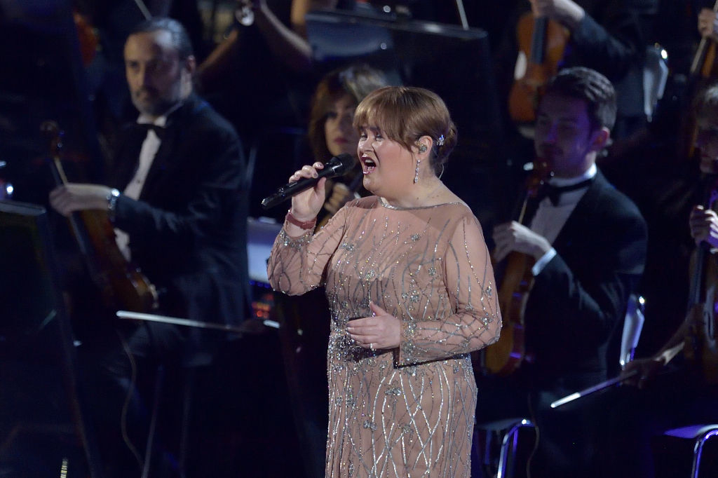 Susan singing on stage with orchestra, wearing a beaded gown