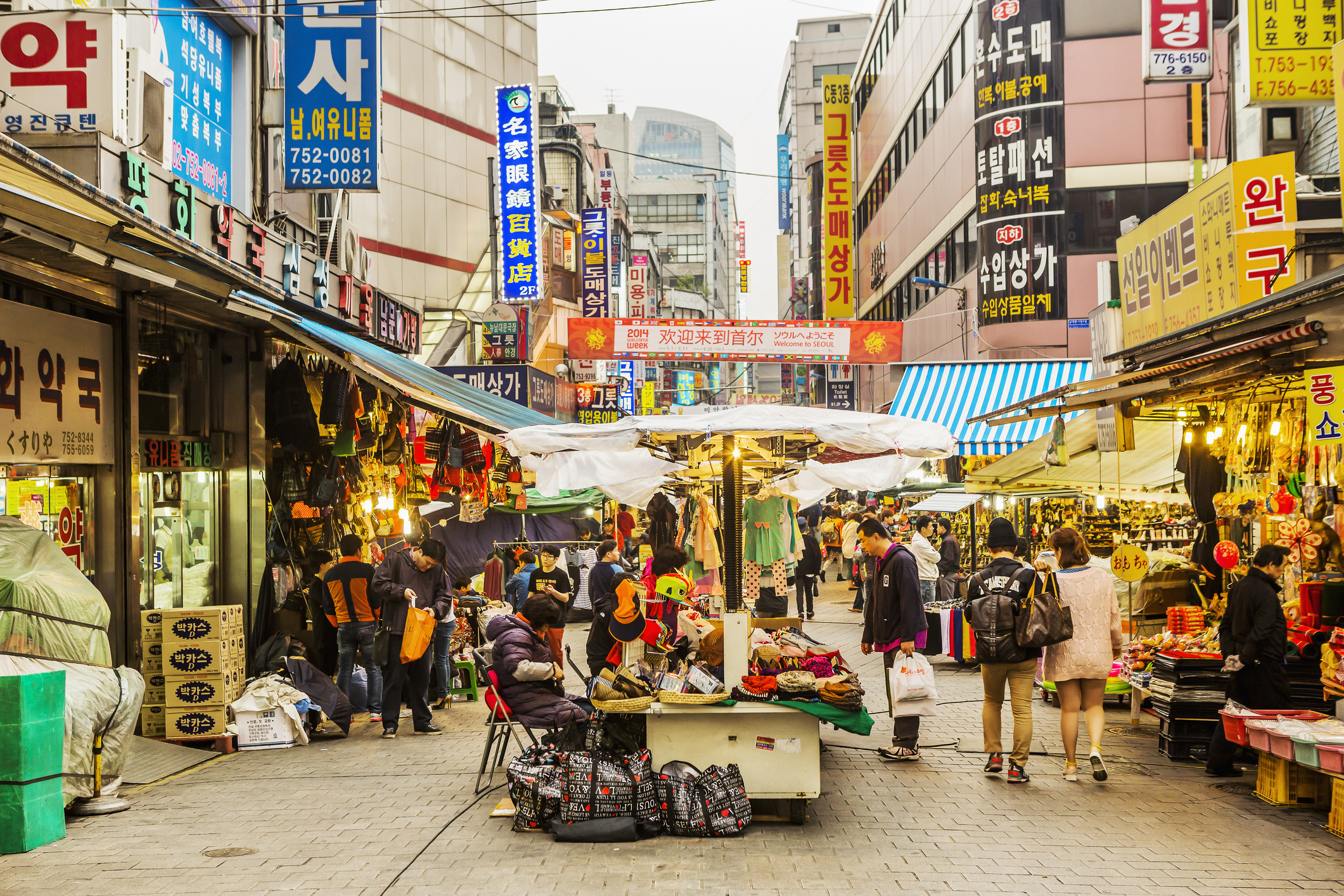 Bustling street market with various stalls and signage, no individuals identified