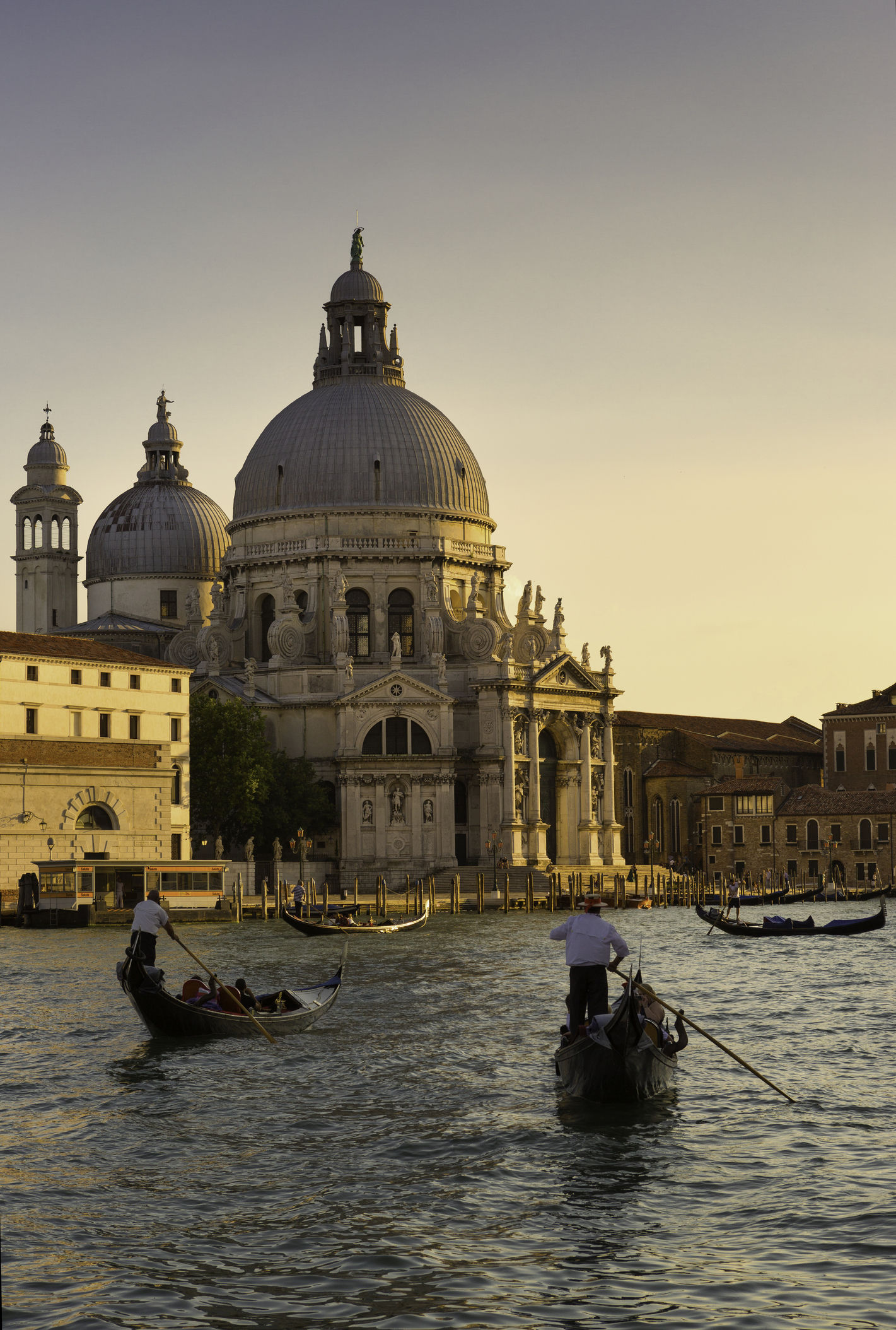 Two gondolas with gondoliers in the foreground and Basilica di Santa Maria della Salute in the background