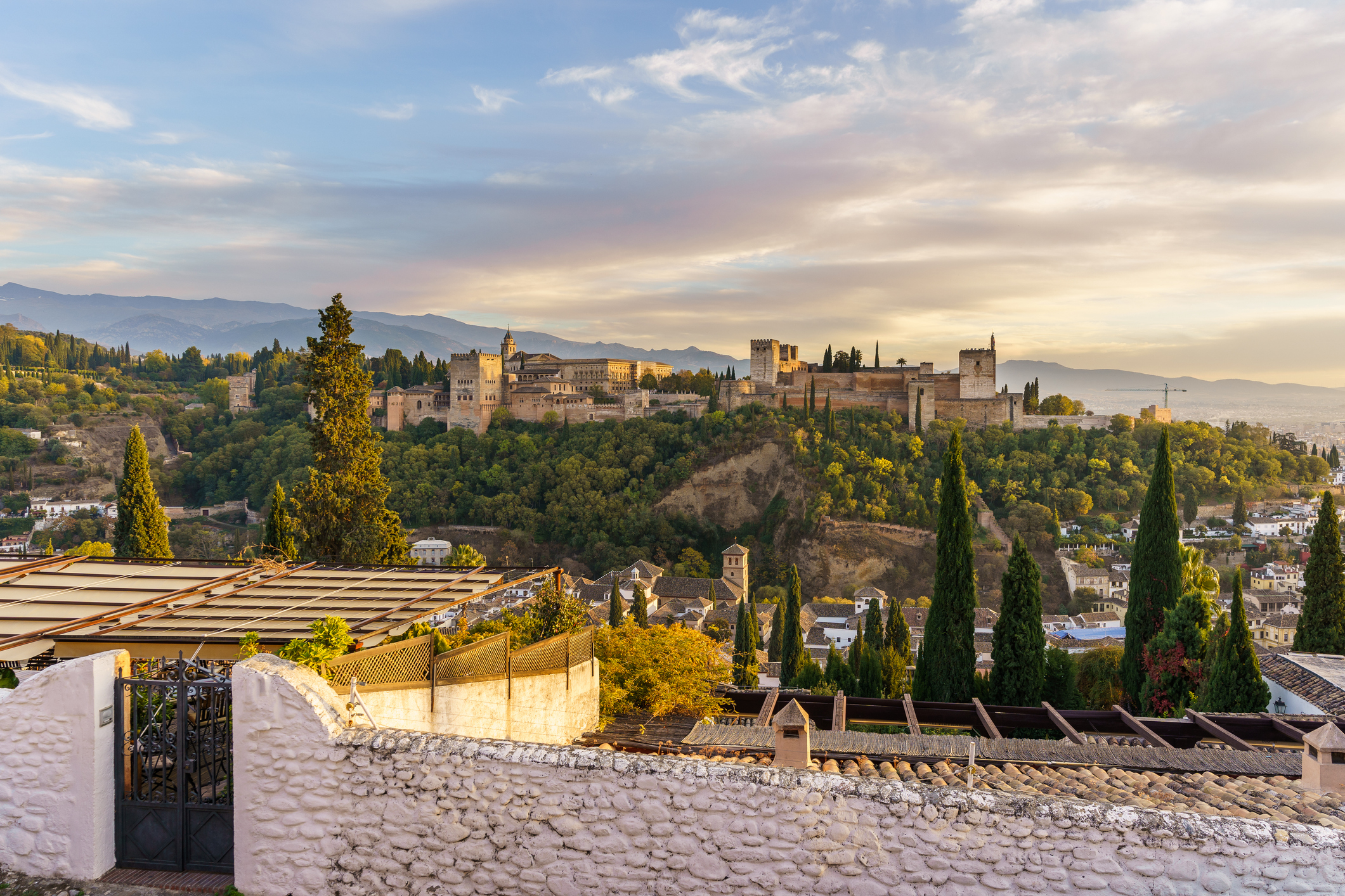 View of Alhambra palace during sunset with trees surrounding the structure
