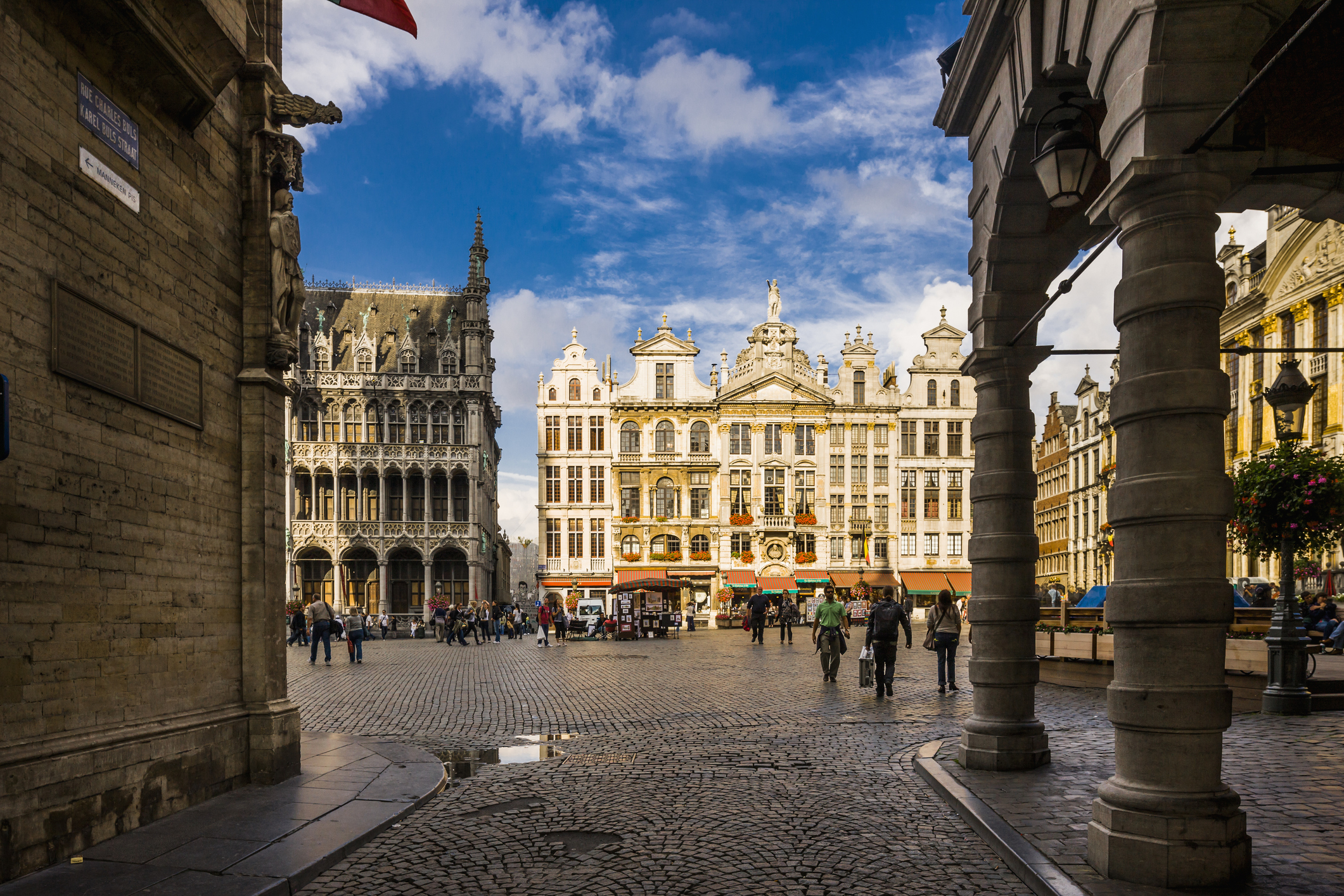 Historic European square lined with ornate buildings and cobblestone streets, bustling with people