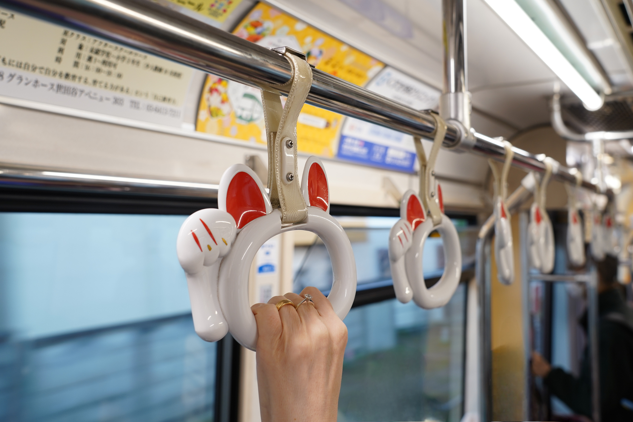 A person&#x27;s hand grasping a subway strap surrounded by similar unoccupied straps