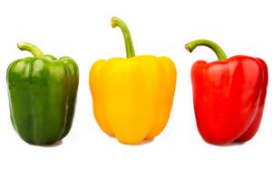 Three bell peppers in green, yellow, and red aligned side by side